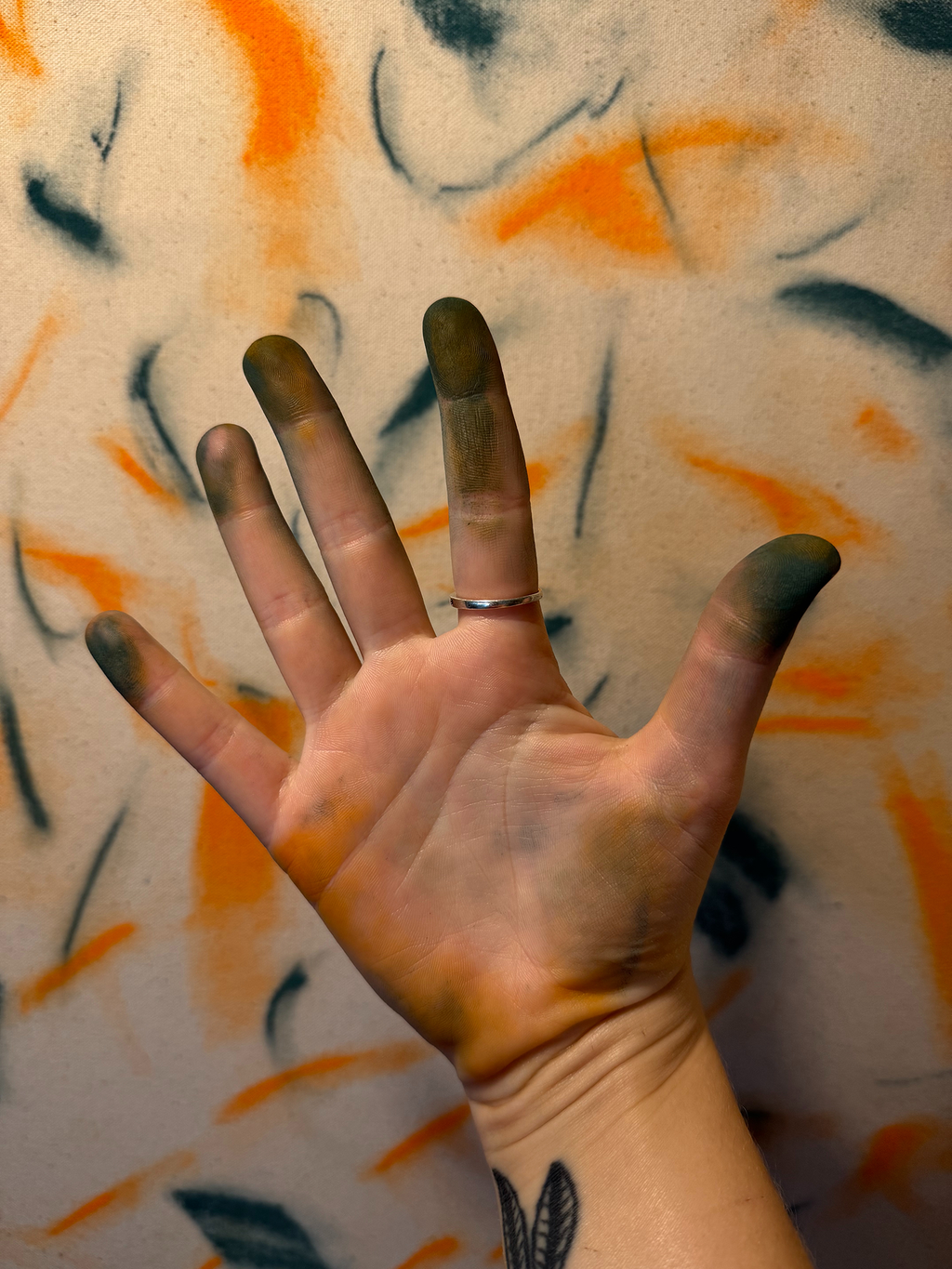 Abstract expressionism artwork on raw cotton canvas. Colours are orange tones, dark and light blue/teal brush strokes. Organic patterns and faces expressing different emotions. Photo of artists hands. Made by Studio Thicia Luiza