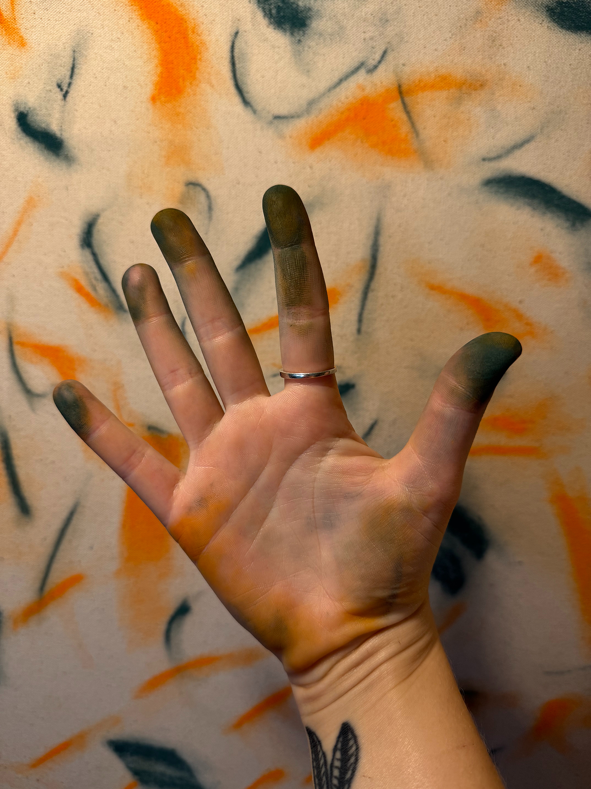 Abstract expressionism artwork on raw cotton canvas. Colours are orange tones, dark and light blue/teal brush strokes. Organic patterns and faces expressing different emotions. Photo of artists hands. Made by Studio Thicia Luiza